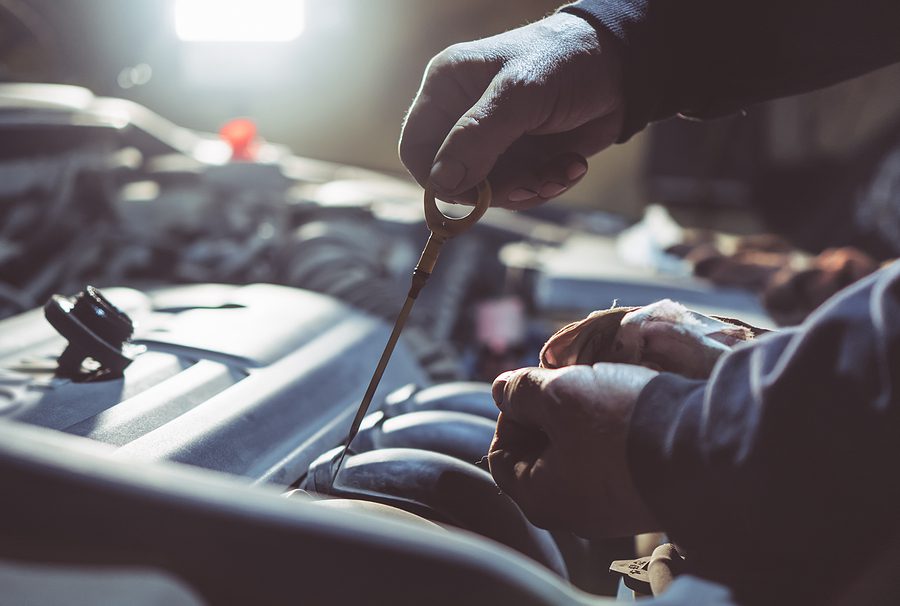 A photo with the text title “Windermere Auto Care: The Pros and Cons of Using Vehicle Oil (Synthetic and Conventional Oil)” and a background of a mechanic changing the car oil.